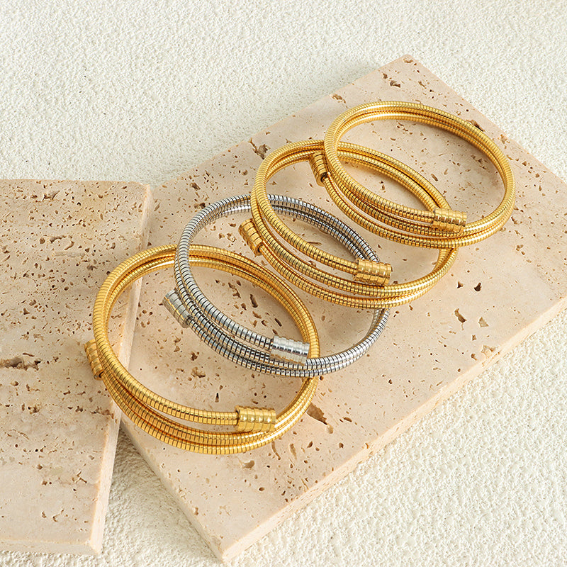 18k gold and silver titanium steel snake bone chain bracelets displayed on stone, stacked versatile style