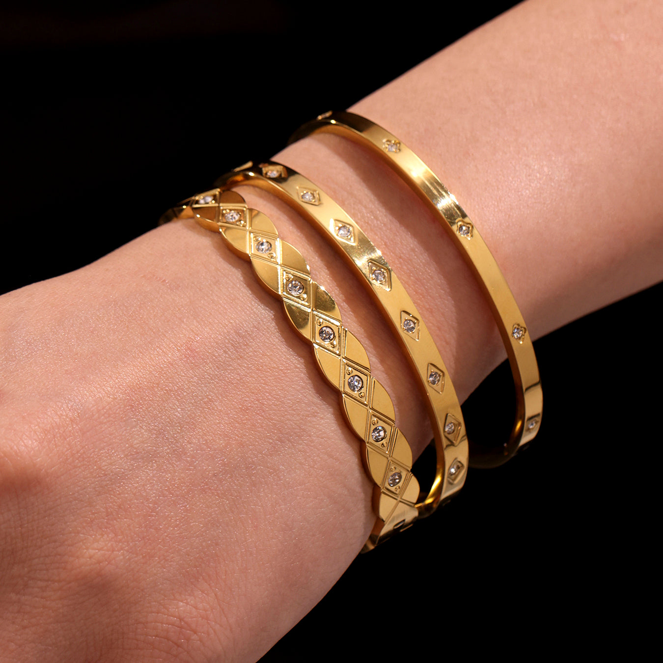 closeup of 18k gold titanium steel zircon bangles stacked on wrist, minimalist fashion accessory