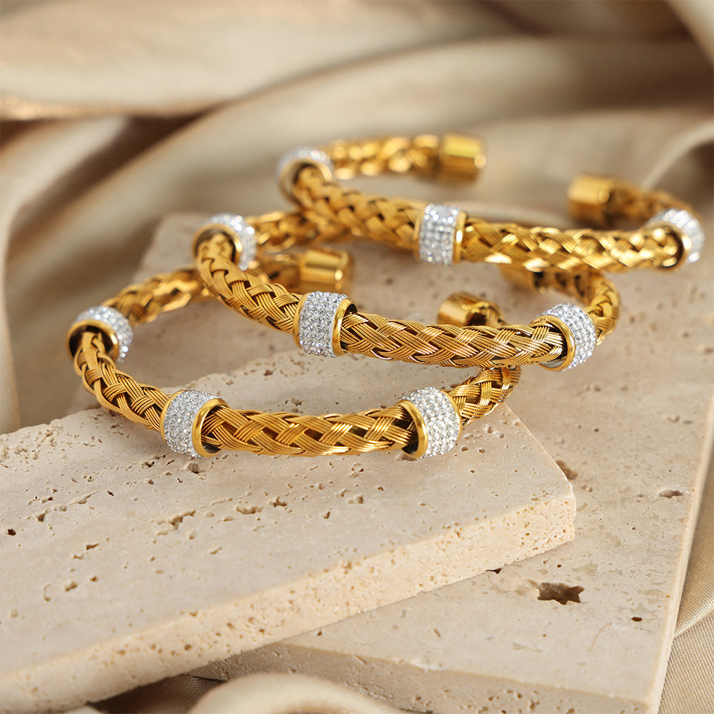 18K PVD gold braided open bangle with CZ accents displayed with matching gold jewelry