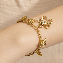 Close-up of an 18K PVD gold floral charm bracelet with butterfly and heart pendants