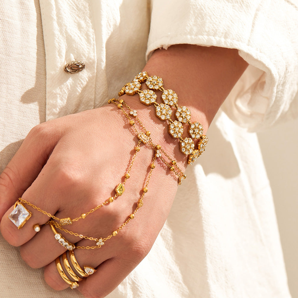 Close-up of CZ flower adjustable bracelet on wrist with 18K PVD gold finish and feminine boutique jewelry styling
