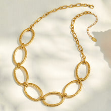 18K PVD gold oval link necklace worn on a model with a black V-neck outfit