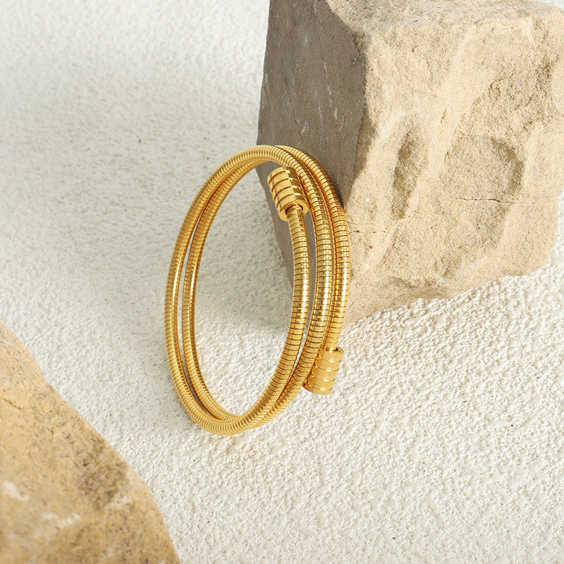 18k gold plated titanium steel snake bone chain bracelet displayed on stone, minimalist fashion scene
