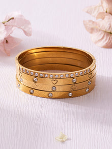 Stacked 18K PVD gold bangles displayed on a light surface