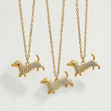 Close-up collection of gold dachshund zircon rings and pendant necklaces on a neutral background