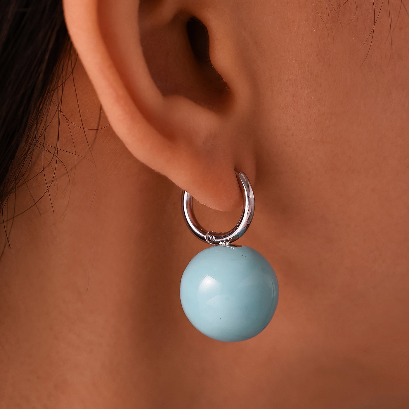 Close-up of a light blue ball drop earring with a steel-tone hoop