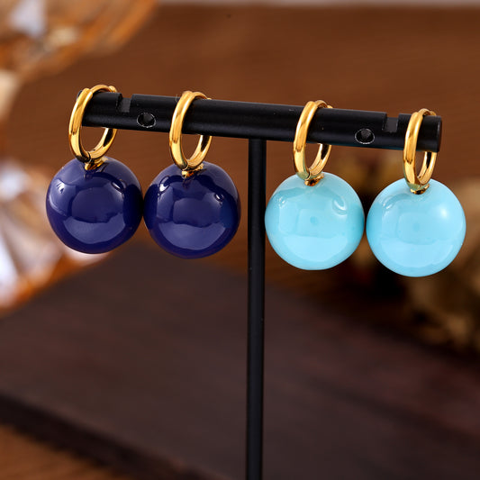 Navy and light blue ball drop hoop earrings displayed on a jewelry stand
