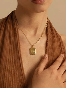 Close-up shot of male model wearing gold plated "where is love" tag necklace, focusing on the engraved pendant and dual chain design