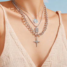 Close-up of layered 316L stainless steel necklaces with cross, starburst and square pendants