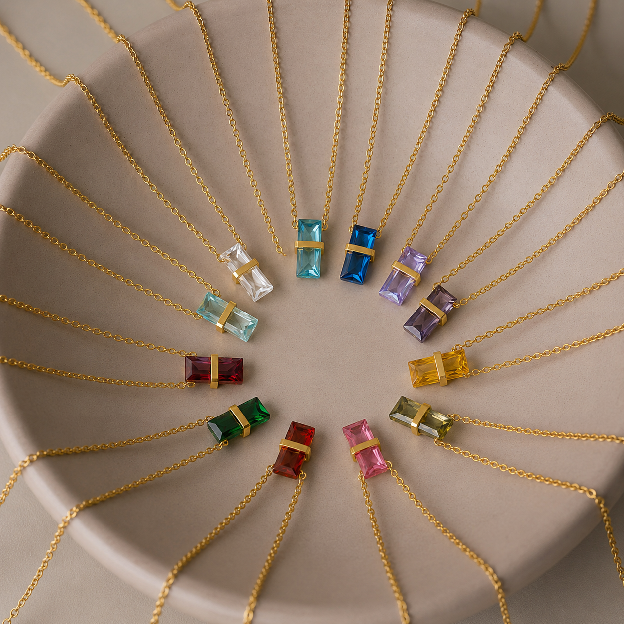 Full 12-color collection of 316L stainless steel birthstone crystal pendant necklaces arranged on a round neutral display tray.