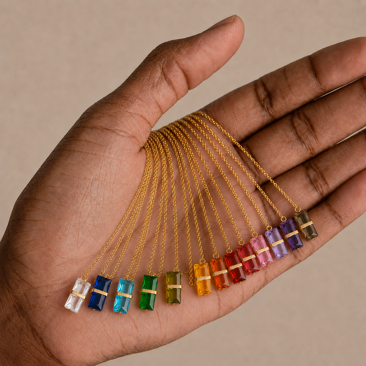 Hand display of 316L stainless steel 12-color birthstone crystal pendant necklaces with colorful rectangular crystal pendants.