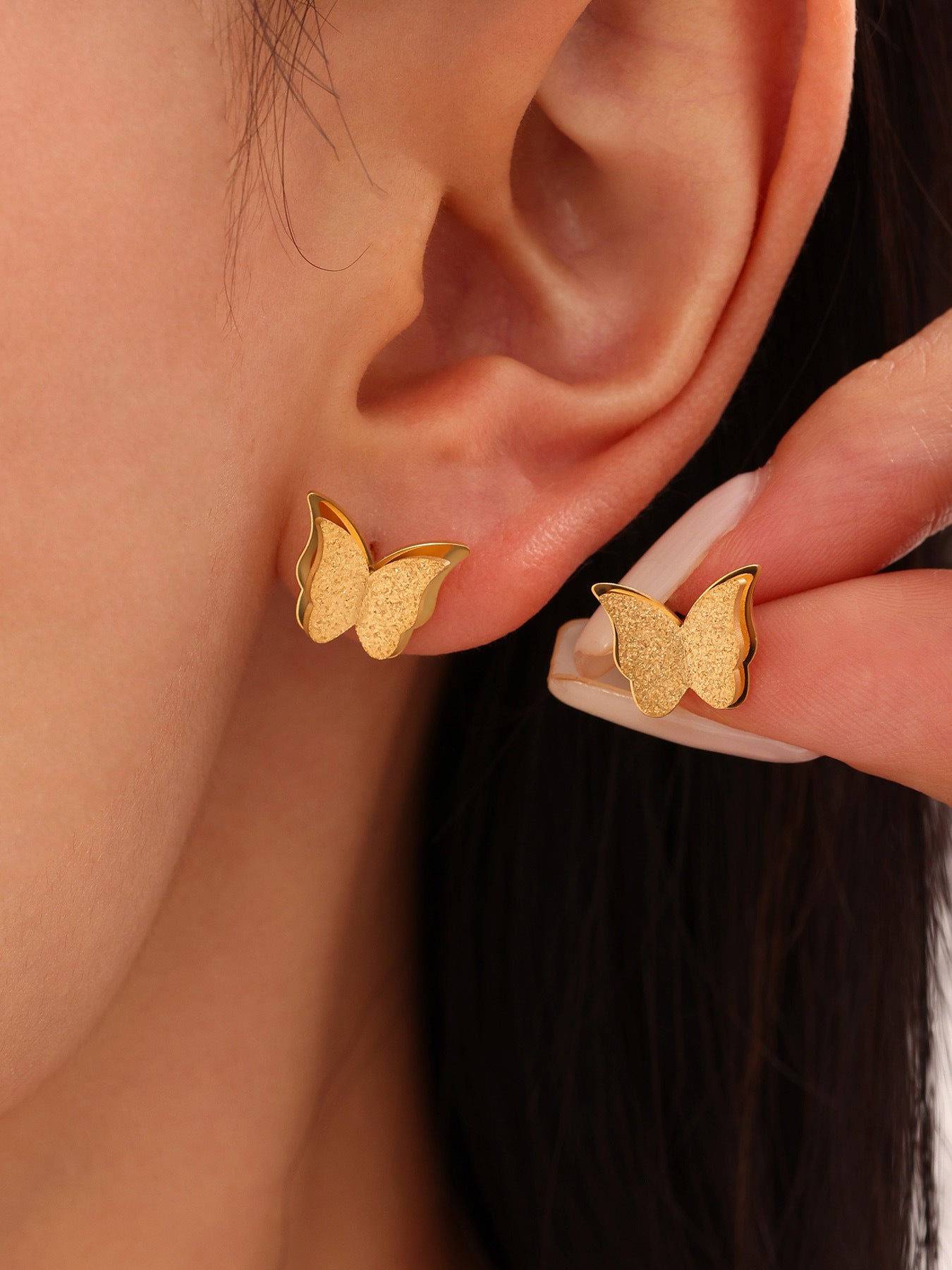 Small butterfly stud earrings worn on the ear, crafted from surgical grade 316L stainless steel for comfortable and hypoallergenic daily wear.