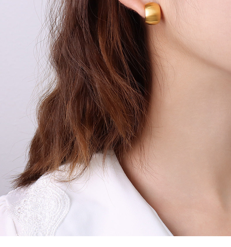 Model wearing minimalist waterproof PVD gold plated thick hoop earrings.