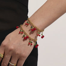 A delicate 18K gold plated cherry bracelet worn on a woman's wrist, featuring waterproof and nickel-free materials.