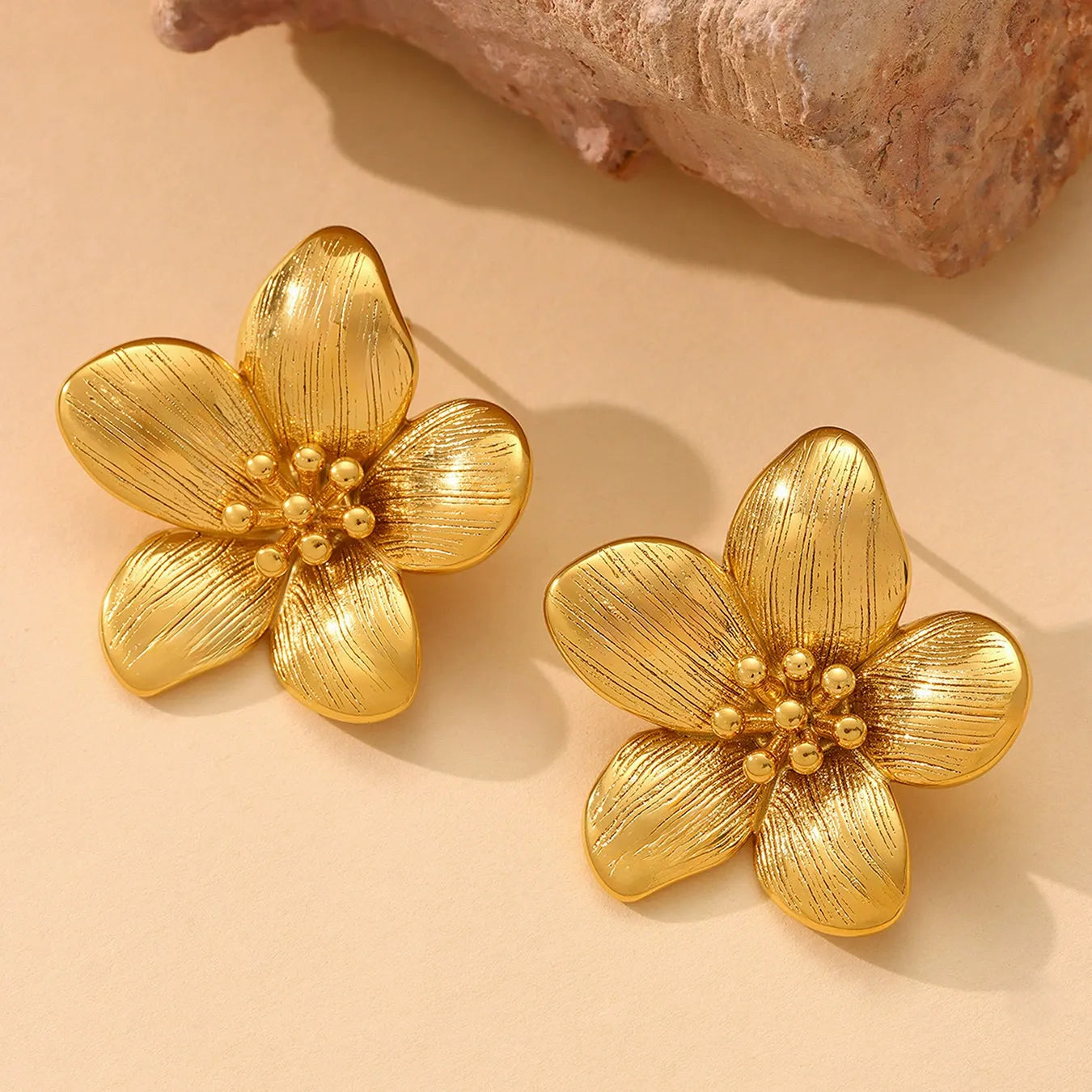 Close up of tarnish-free botanical jewelry featuring 18K gold plated stainless steel sunflower earrings.