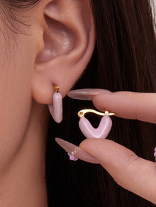 Close up of woman wearing Y2K style pink enamel heart hoop earrings for sensitive ears.