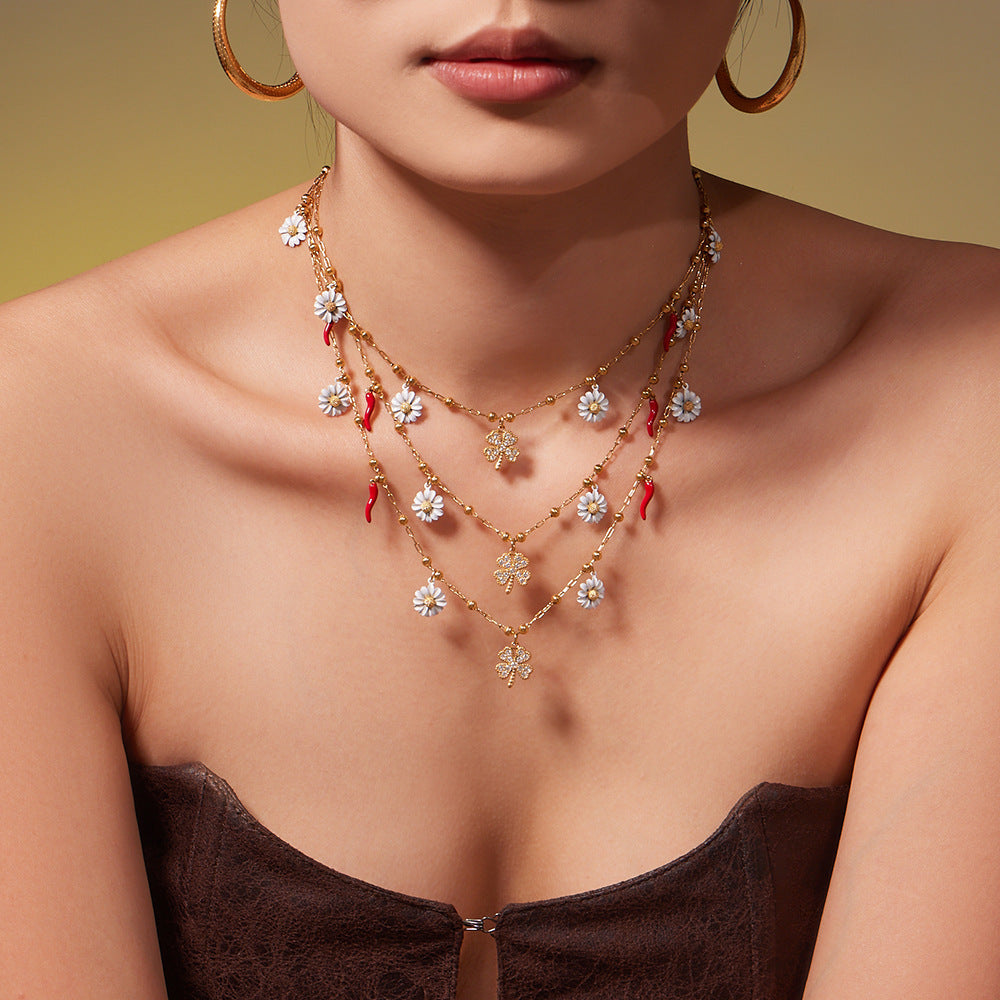 A woman wearing a dainty hypoallergenic daisy and clover pendant necklace made of 18K gold plated stainless steel for a romantic look.