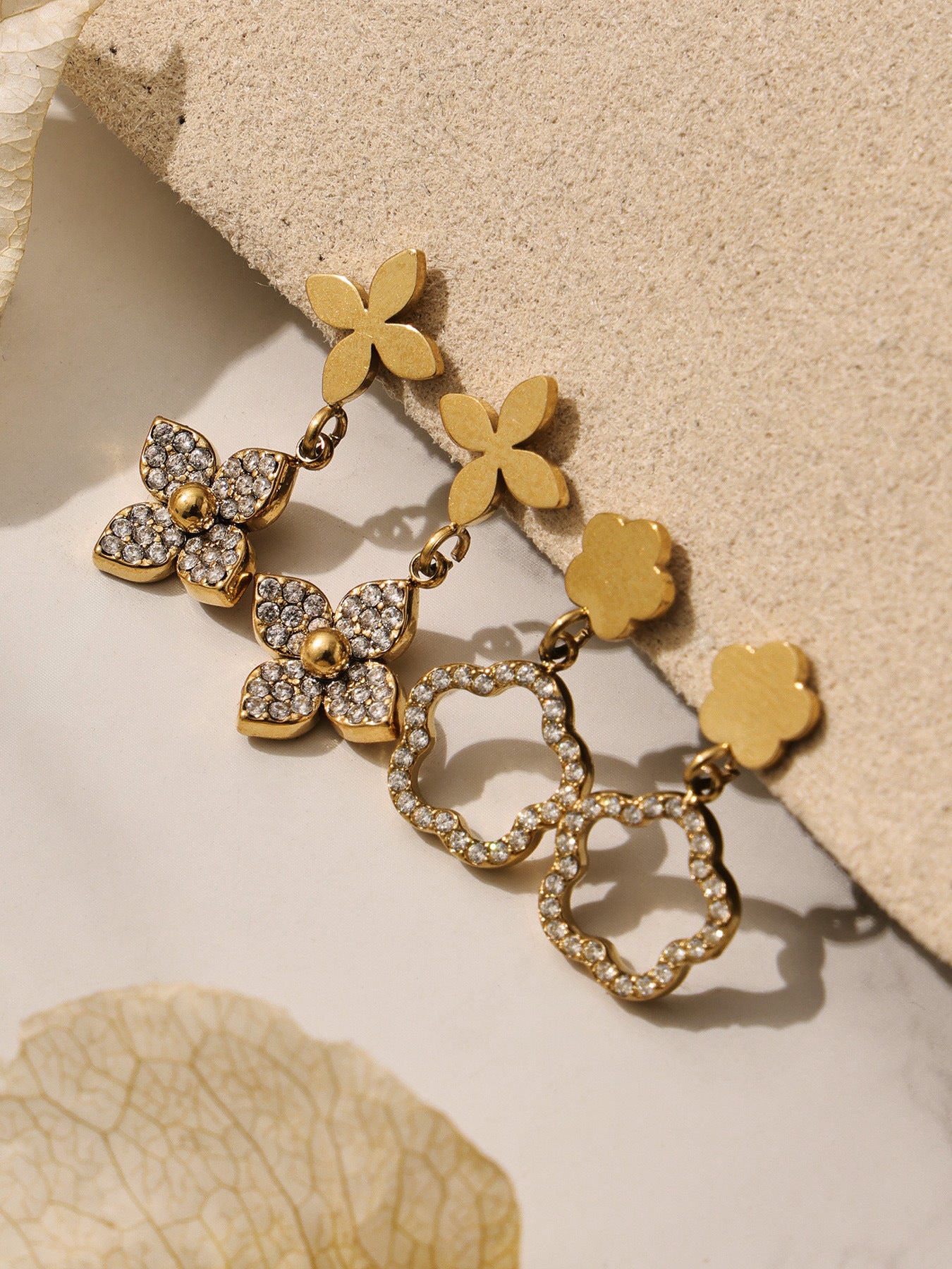 Pair of flower-shaped stud earrings and dangling geometric earrings made of hypoallergenic 316L stainless steel.