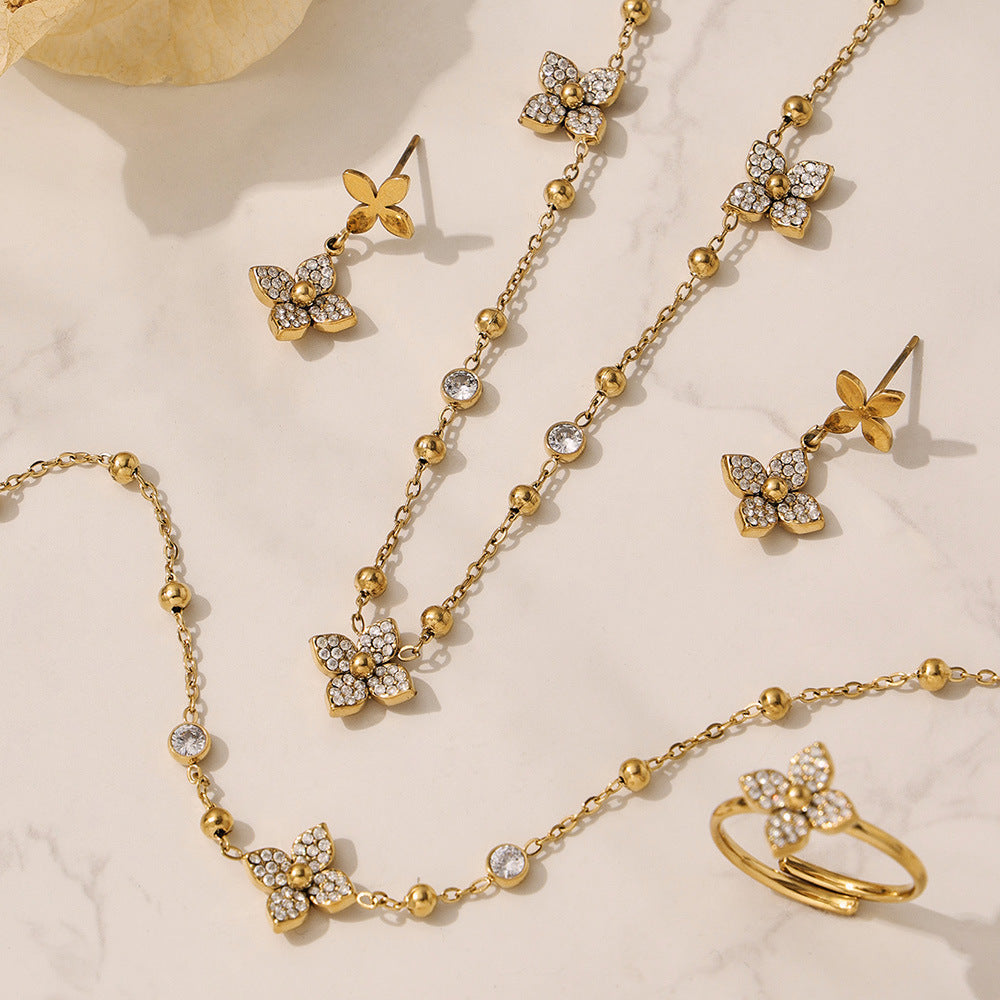 Aesthetic flat lay of the 316L stainless steel flower zircon jewelry collection on a warm textured background.