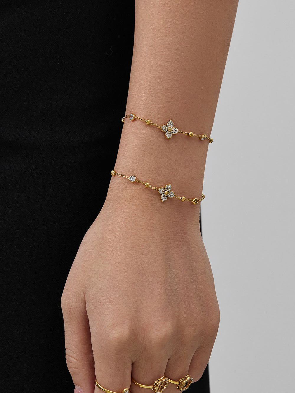 Sparkling zircon flower ring and matching gold bracelet shown together on a hand for a sophisticated jewelry style.