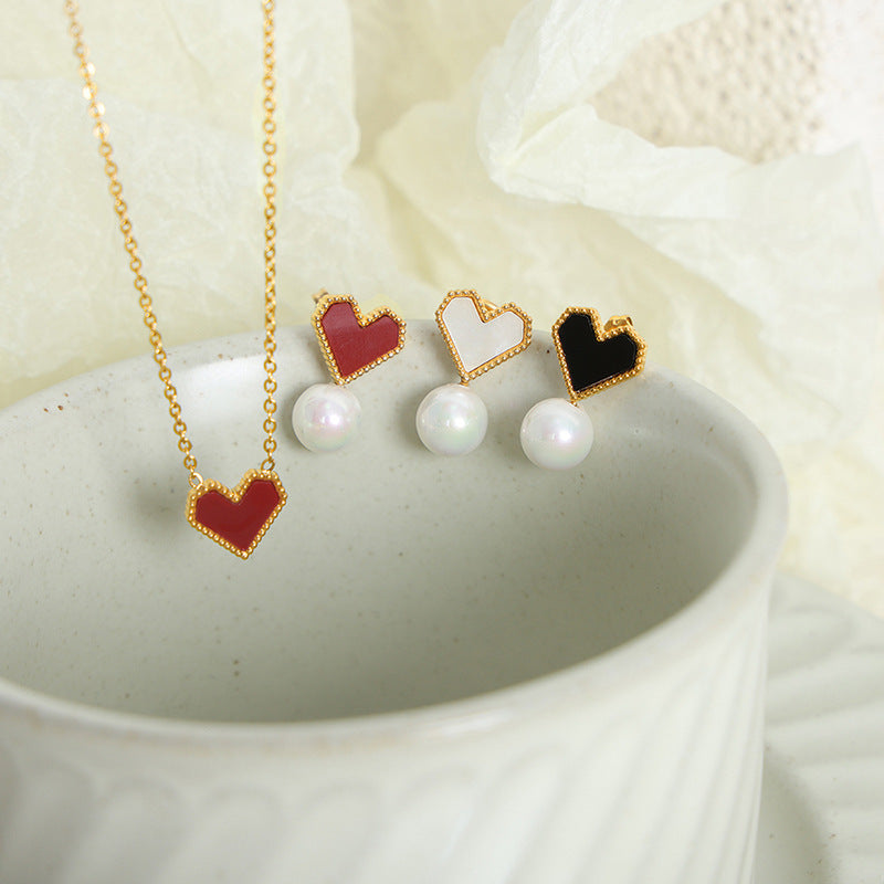 Various French heart necklaces and pearl earrings arranged in a bowl, perfect for aesthetic jewelry branding.