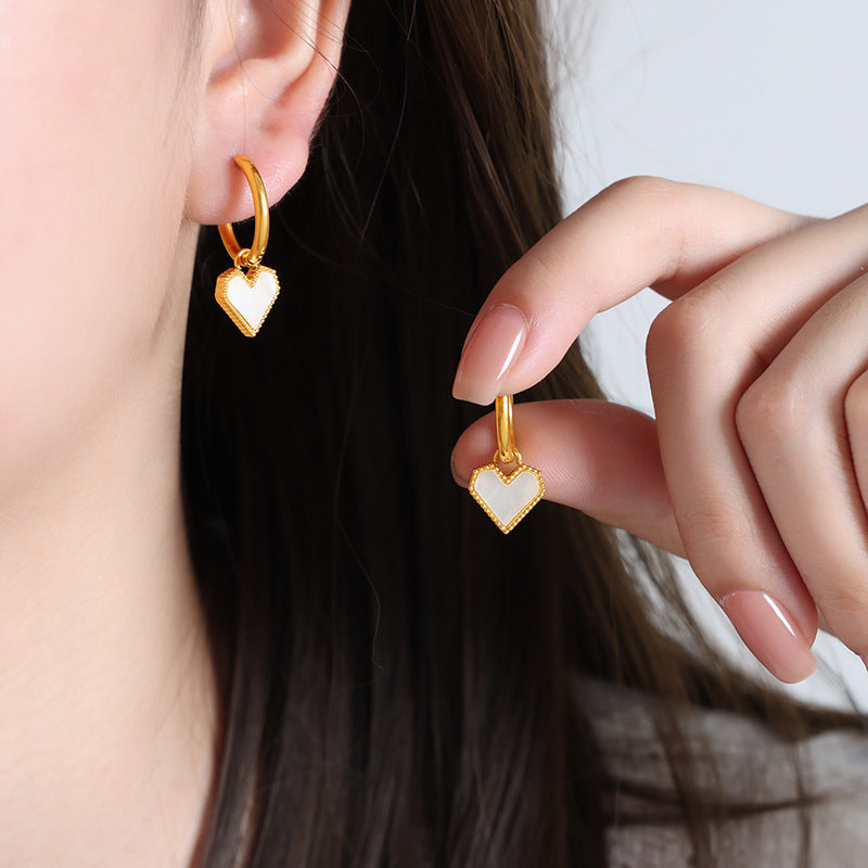 Detail of hypoallergenic white heart earrings with a delicate pearl accent worn by a model for daily elegance.