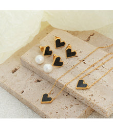 Multiple styles of heart-shaped earrings and necklaces displayed on a jewelry tray for wholesale selection.