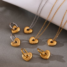 A mix of gold and two-tone puffed heart pendants and earrings showing the high-shine, waterproof finish.