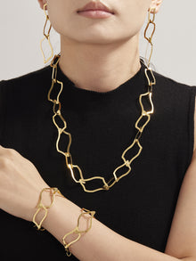 Close up of a woman styled with the 18K gold plated geometric jewelry collection, demonstrating its radiant finish on sensitive skin.