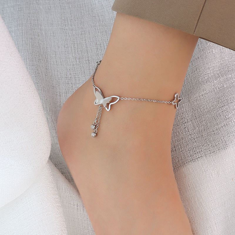 Delicate gold butterfly tassel anklet on a woman's ankle, star accents and thin chain for a romantic layered look