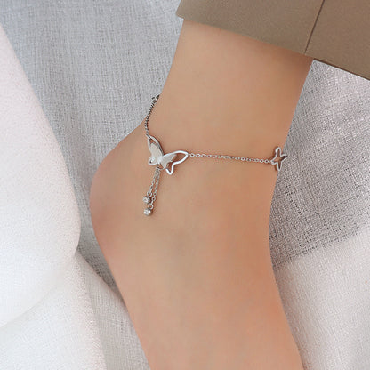 Delicate gold butterfly tassel anklet on a woman's ankle, star accents and thin chain for a romantic layered look