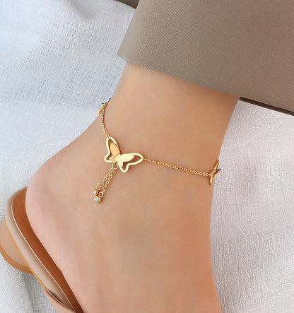 Soft focus shot of gold butterfly tassel anklet on a foot, lightweight design and adjustable fit for sensitive skin