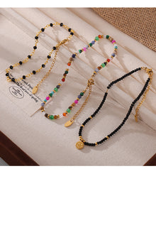 Top-down flat lay of multiple colorful natural stone beaded anklets on neutral background, 316L stainless steel construction and gold plating for sensitive skin