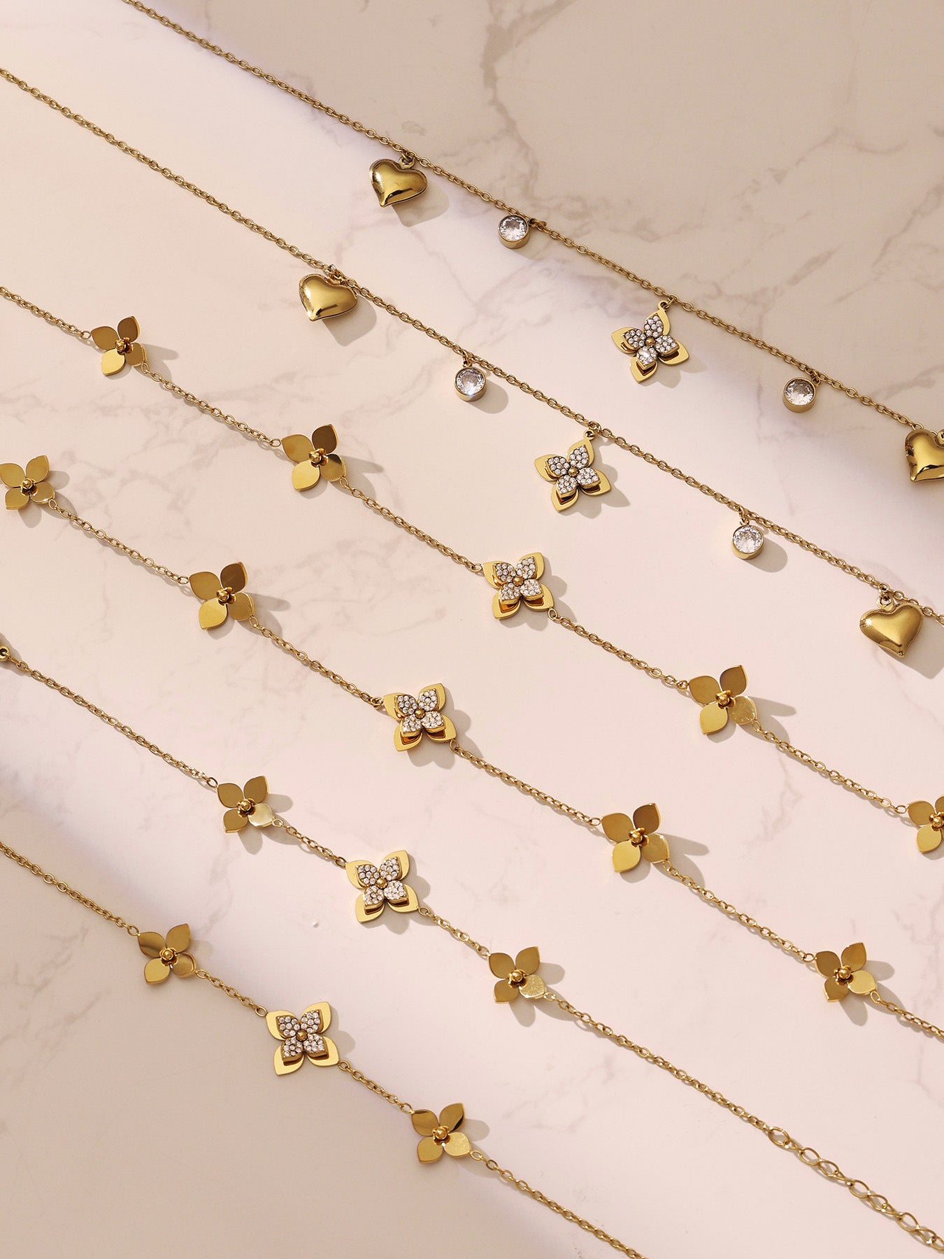 Sparkling four-petal flower pendant necklaces displayed together, highlighting the anti-corrosion and skin-safe properties.