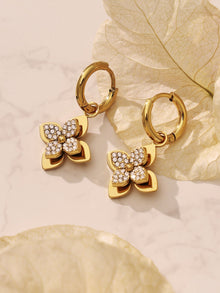 Hand holding a pair of clover-style four-petal flower earrings made of waterproof 316L stainless steel.