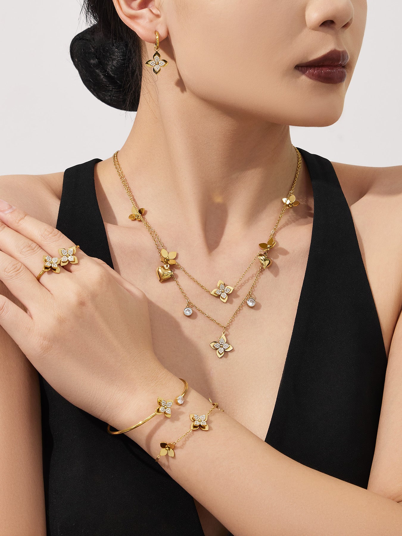 A model wearing layered 18K gold plated four-petal flower necklaces for an elegant and hypoallergenic jewelry look on sensitive skin.