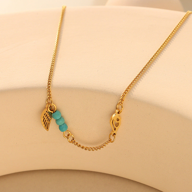 Delicate gold turquoise wing anklet flat lay on neutral background, 316L stainless steel construction and PVD gold plating for sensitive skin