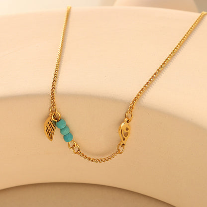 Delicate gold turquoise wing anklet flat lay on neutral background, 316L stainless steel construction and PVD gold plating for sensitive skin