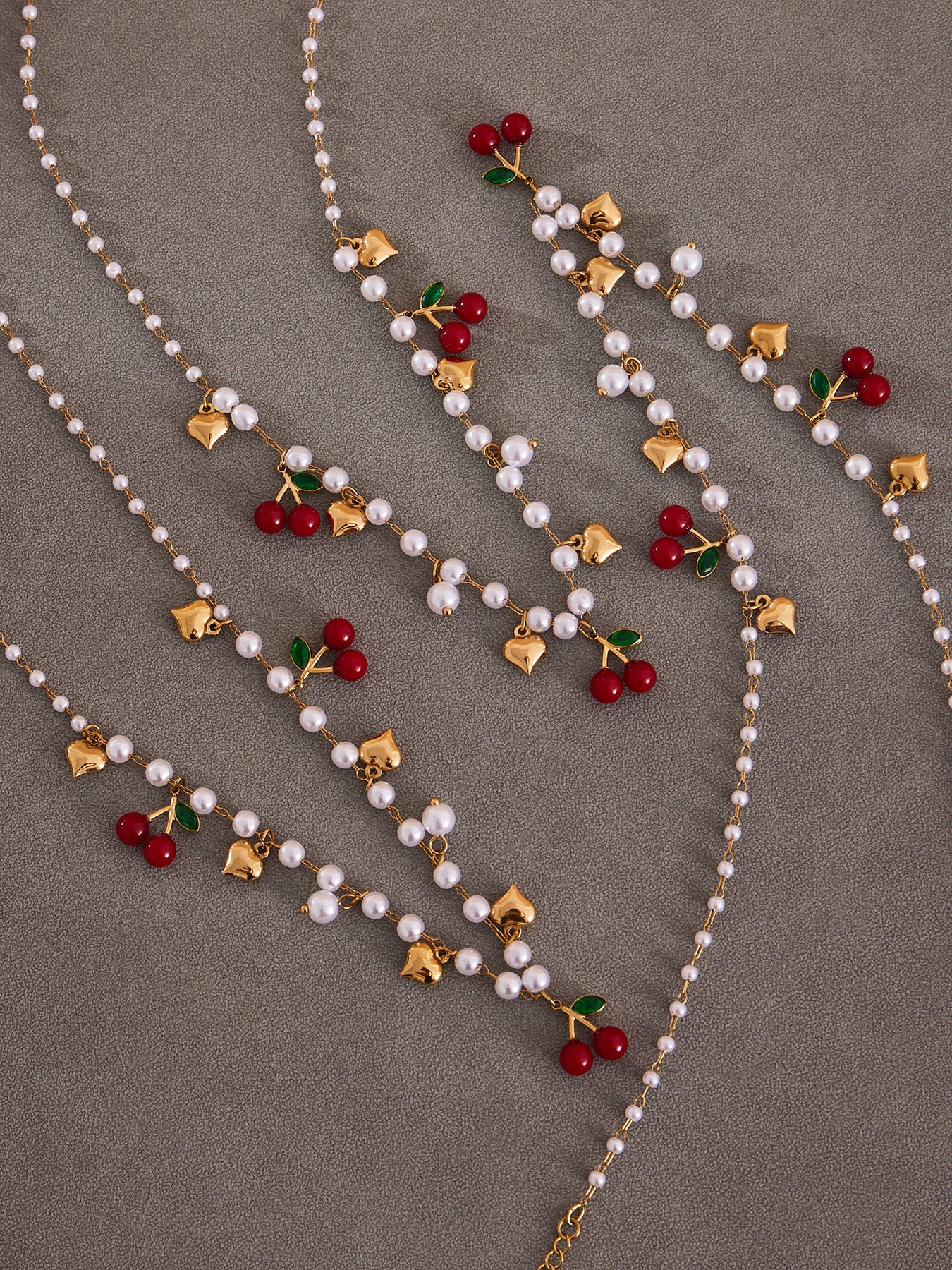 Detailed view of the hypoallergenic imitation pearls and red cherry charms on a tarnish-resistant gold beaded chain.