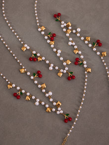 Detailed view of the hypoallergenic imitation pearls and red cherry charms on a tarnish-resistant gold beaded chain.