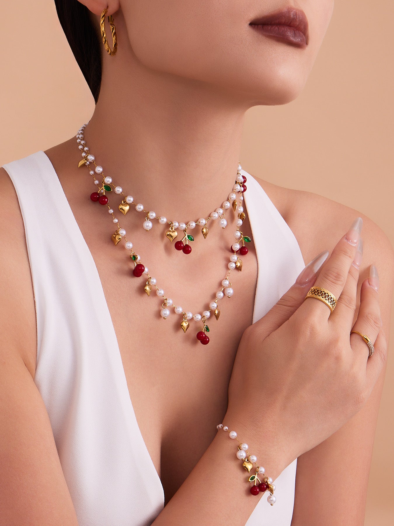 A woman wearing a layered hypoallergenic beaded necklace with red cherry and gold heart charms on sensitive skin.