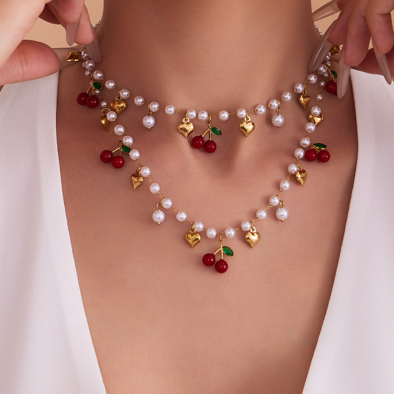 Beautifully layered 18K gold plated beaded jewelry featuring vibrant red cherry charms and white imitation pearls.