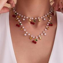 Beautifully layered 18K gold plated beaded jewelry featuring vibrant red cherry charms and white imitation pearls.