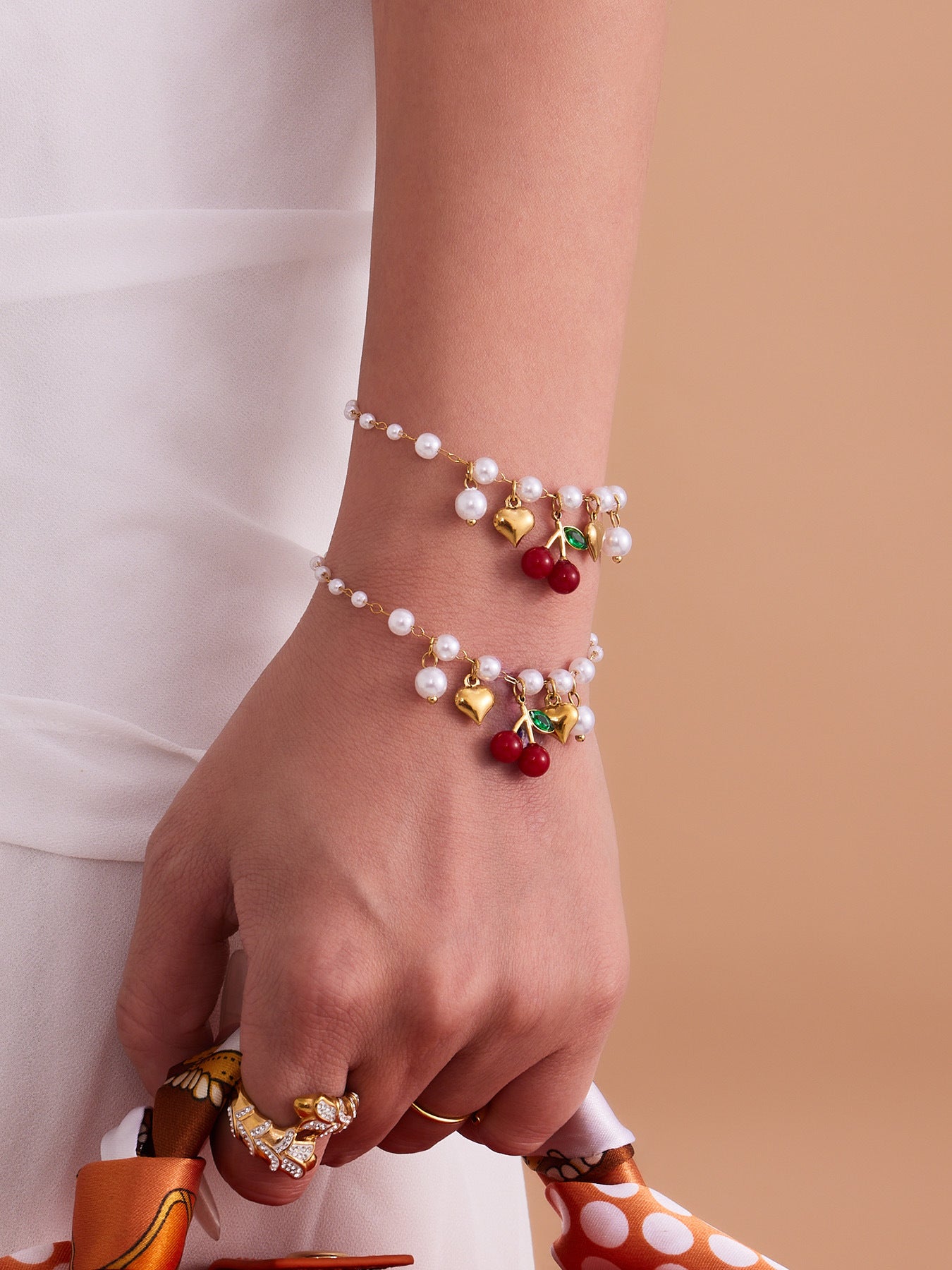 Matching beaded bracelet featuring red cherry and golden heart pendants, highlighting its durable and skin-safe design.