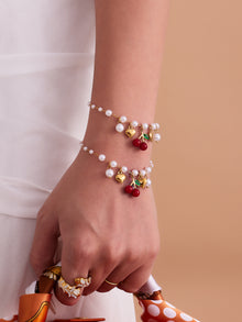 Matching beaded bracelet featuring red cherry and golden heart pendants, highlighting its durable and skin-safe design.