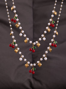High-quality 18K gold PVD plated beaded jewelry set featuring red cherries and pearls on a dark aesthetic background.
