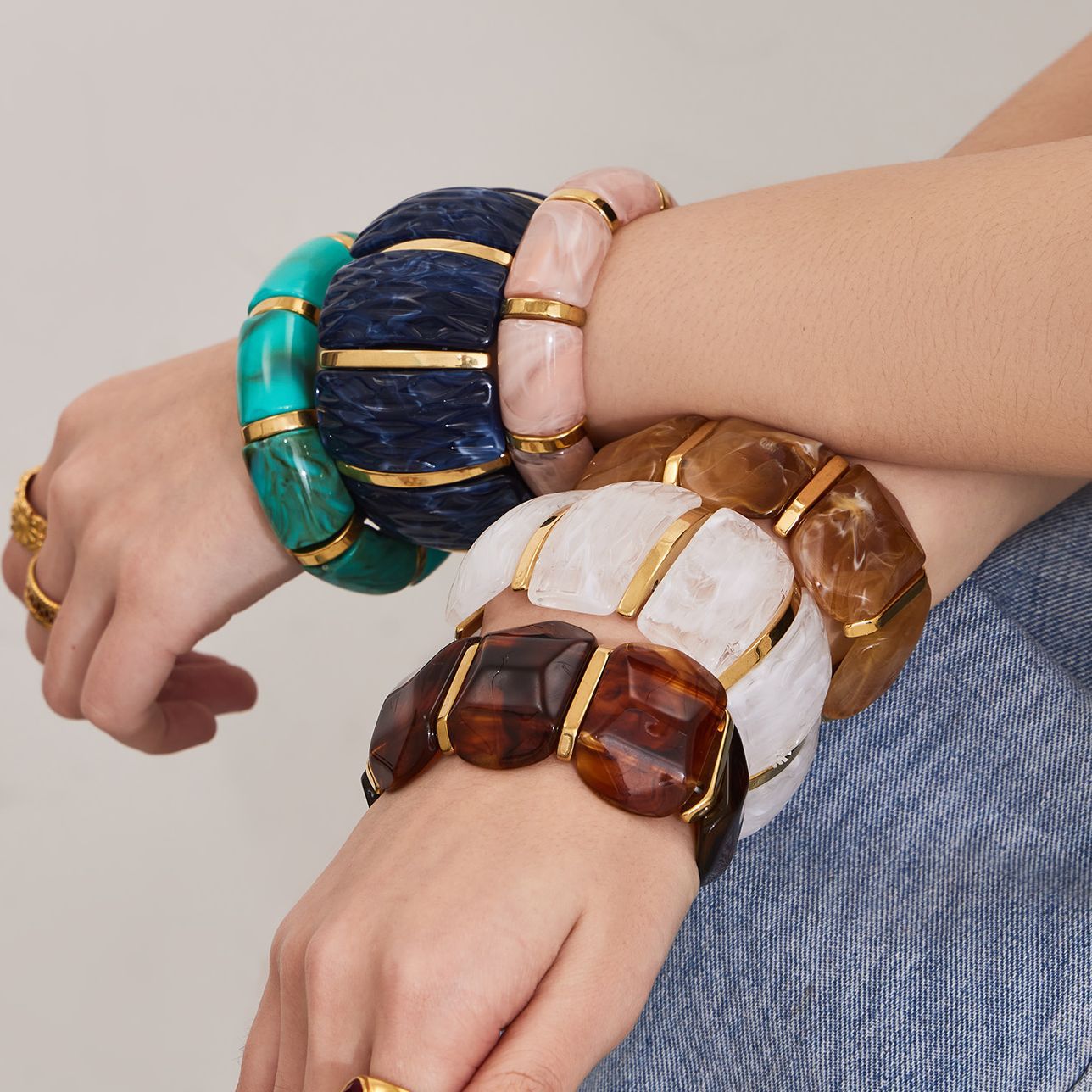 Stacked colorful wide resin bracelets with gold stainless steel parts on wrist styling