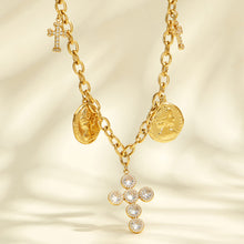 Close-up of a clear zircon cross pendant and engraved coin charms on gold-tone chains