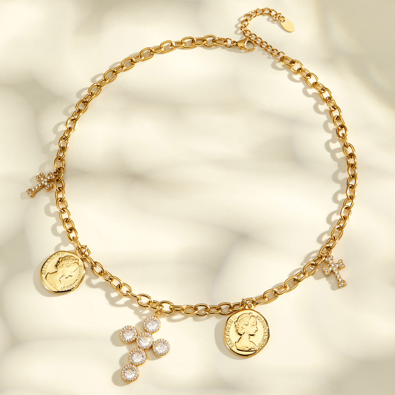 Full view of a gold-tone charm necklace with coin pendants and a central zircon cross