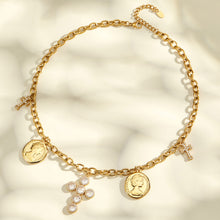 Full view of a gold-tone charm necklace with coin pendants and a central zircon cross